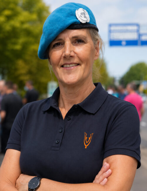 Vrouwelijke Nederlandse veteraan met blauwe VN-baret draagt een Veteran Unity damespolo in Blue Midnight.